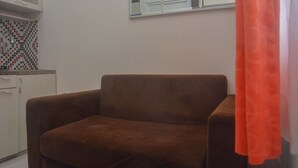 A brown armchair in a room with a tiled backsplash and a window with a view. - Comfy And Best Deal 2Br At Green Pramuka City Apartment (Jakarta)