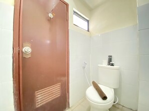 A bathroom with a brown door, white tiled walls, a white toilet, and a window above the toilet. - Spacious 3Br At Gateway Ahmad Yani Cicadas Apartment (Bandung)