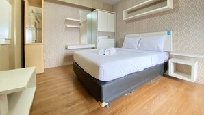 A hotel room with a bed, a desk, a mirror, and built-in shelves. - Spacious 3Br At Gateway Ahmad Yani Cicadas Apartment (Bandung)