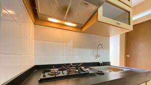 A kitchen with a gas stove, a sink, and a window above the sink. - Spacious 3Br At Gateway Ahmad Yani Cicadas Apartment (Bandung)
