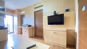 A modern kitchen with a flat-screen TV, wooden cabinets, and a remote control on a table. - Spacious 3Br At Gateway Ahmad Yani Cicadas Apartment (Bandung)
