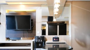 A modern kitchen with a flat-screen TV, a coffee machine, and a minibar. - Best View And Cozy Living 2Br At Tamansari Papilio Apartment (Surabaya)