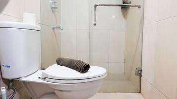 A bathroom with a toilet, a shower, and a handrail.