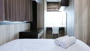 A hotel room with a bed, a desk, a chair, and a large window. - Best View And Cozy Living 2Br At Tamansari Papilio Apartment (Surabaya)