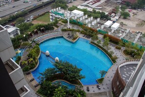 A rooftop swimming pool with a circular design, surrounded by greenery and modern buildings. - Scenic And Comfortable Studio At West Vista Apartment (Jakarta)