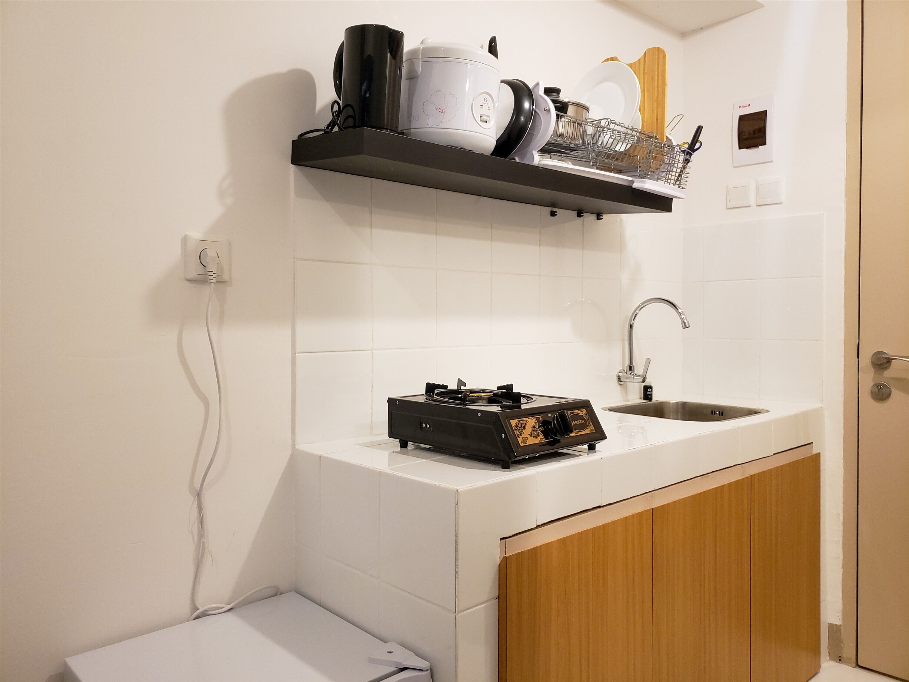 A compact kitchen with a white countertop, a built-in stove, a sink, and a wooden cabinet.