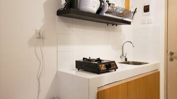 A compact kitchen with a white countertop, a built-in stove, a sink, and a wooden cabinet.