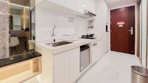 A modern kitchen with white cabinetry, a stainless steel sink, and a built-in dishwasher. - Scenic And Restful Studio Sky House Bsd Apartment (Pagedangan)