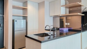 Une cuisine moderne dotée d’un réfrigérateur encastré, d’un plan de travail noir et d’un robinet en acier inoxydable.