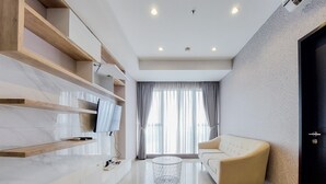 Un salon moderne avec un canapé, un téléviseur fixé au mur et une table basse ronde.