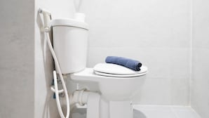 Un inodoro blanco con una toalla azul sobre el asiento y un dispensador de papel higiénico adherido al tanque.