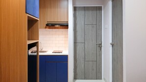 Una cocina compacta con armarios de madera, una encimera y una puerta que da a otra habitación.