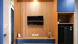 Una cocina moderna con una televisión de pantalla plana integrada, armarios de madera y un refrigerador negro.