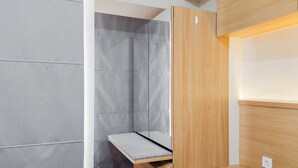 A modern room with a built-in bench, a wooden cabinet, and a grey wall. - Comfortable Studio Apartment At M-Town Residence (Gading Serpong)