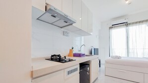 A modern kitchen with a built-in dishwasher, a compact stove, and a window with sheer curtains.