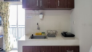 A compact kitchen with wooden cabinets, a built-in sink, and a small countertop. - Warm And Cozy Studio At Cinere Resort Apartment (Depok)