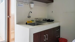 A compact kitchen with a sink, a dish rack, and a small countertop. - Warm And Cozy Studio At Cinere Resort Apartment (Depok)