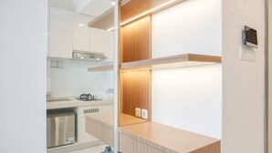 A modern kitchen with white cabinets, wooden countertops, and built-in appliances. - Comfy And Warm Studio Room At Sky House Bsd Apartment (Pagedangan)