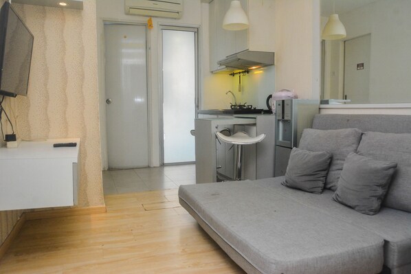 A compact living space with a kitchenette, a sofa, and a television.