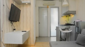 A compact room with a built-in TV, a small kitchenette, a white sink, and a sofa. - Minimalist And Warm 2Br At Bassura City Apartment (Jakarta)