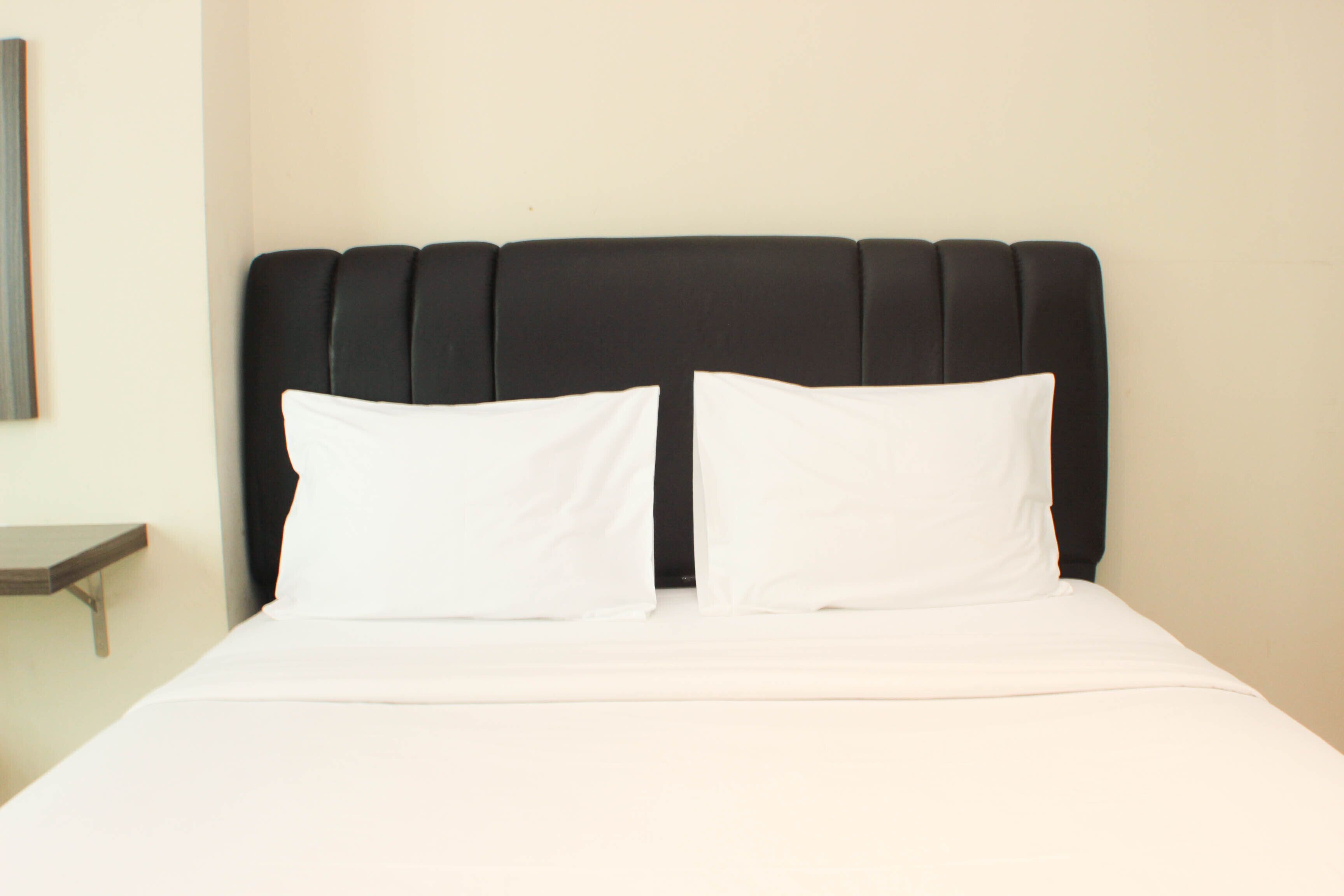 A bed with a black headboard and two white pillows.