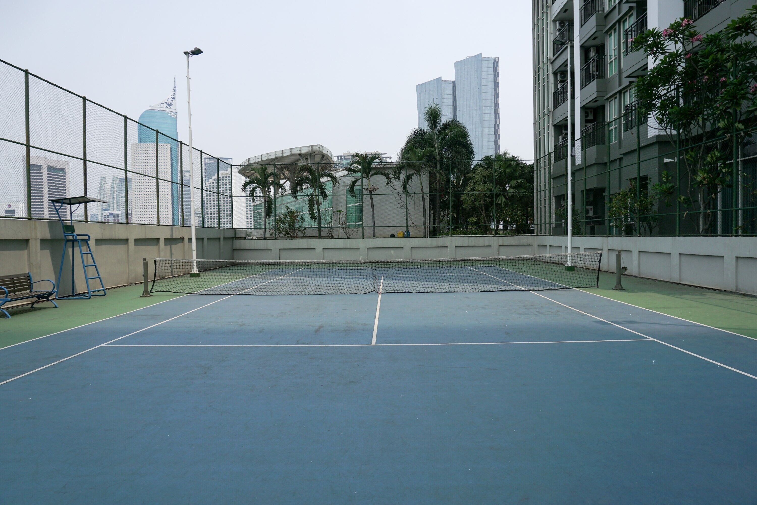 An indoor tennis court with a net, benches, and a fence.