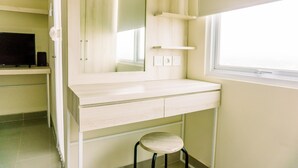 Une salle de bain avec un meuble-lavabo blanc, un miroir, un petit tabouret et une fenêtre.
