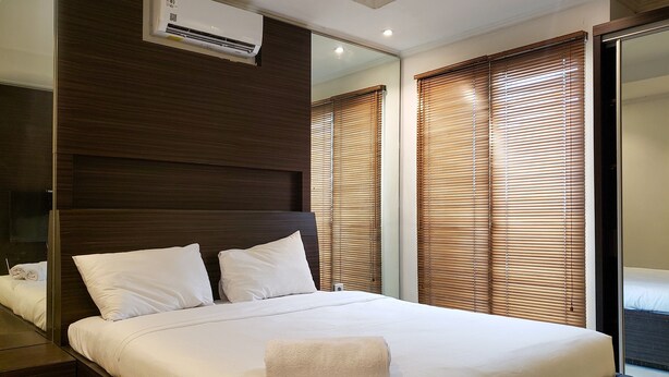 A modern bedroom with a large bed, wooden headboard, and a built-in air conditioning unit.