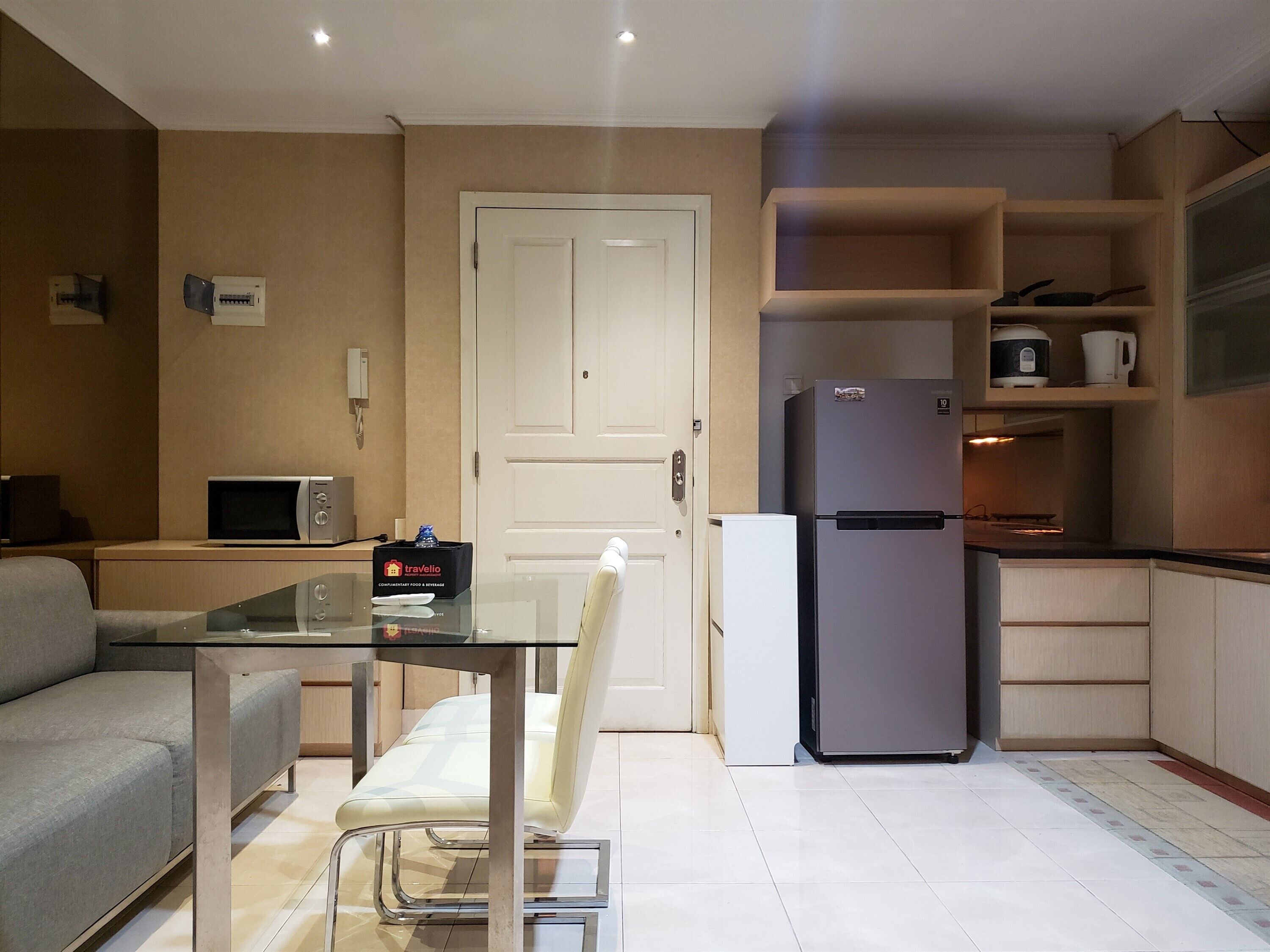 A compact kitchen with a refrigerator, microwave, and a small dining table with a chair.