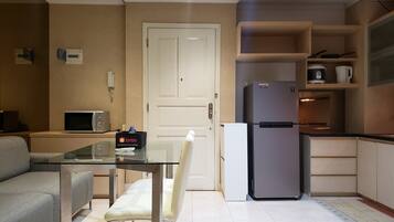 A compact kitchen with a refrigerator, microwave, and a small dining table with a chair.