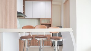 A modern kitchen with a white countertop, three bar stools with metal legs, and wooden cabinets.