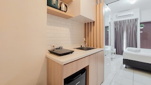 A compact kitchen with a sink, countertop, and wooden cabinets. - Nice Studio Apartment At M-Town Residence (Gading Serpong)