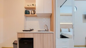 A compact kitchenette with a sink, countertop, and storage cabinets. - Nice Studio Apartment At M-Town Residence (Gading Serpong)