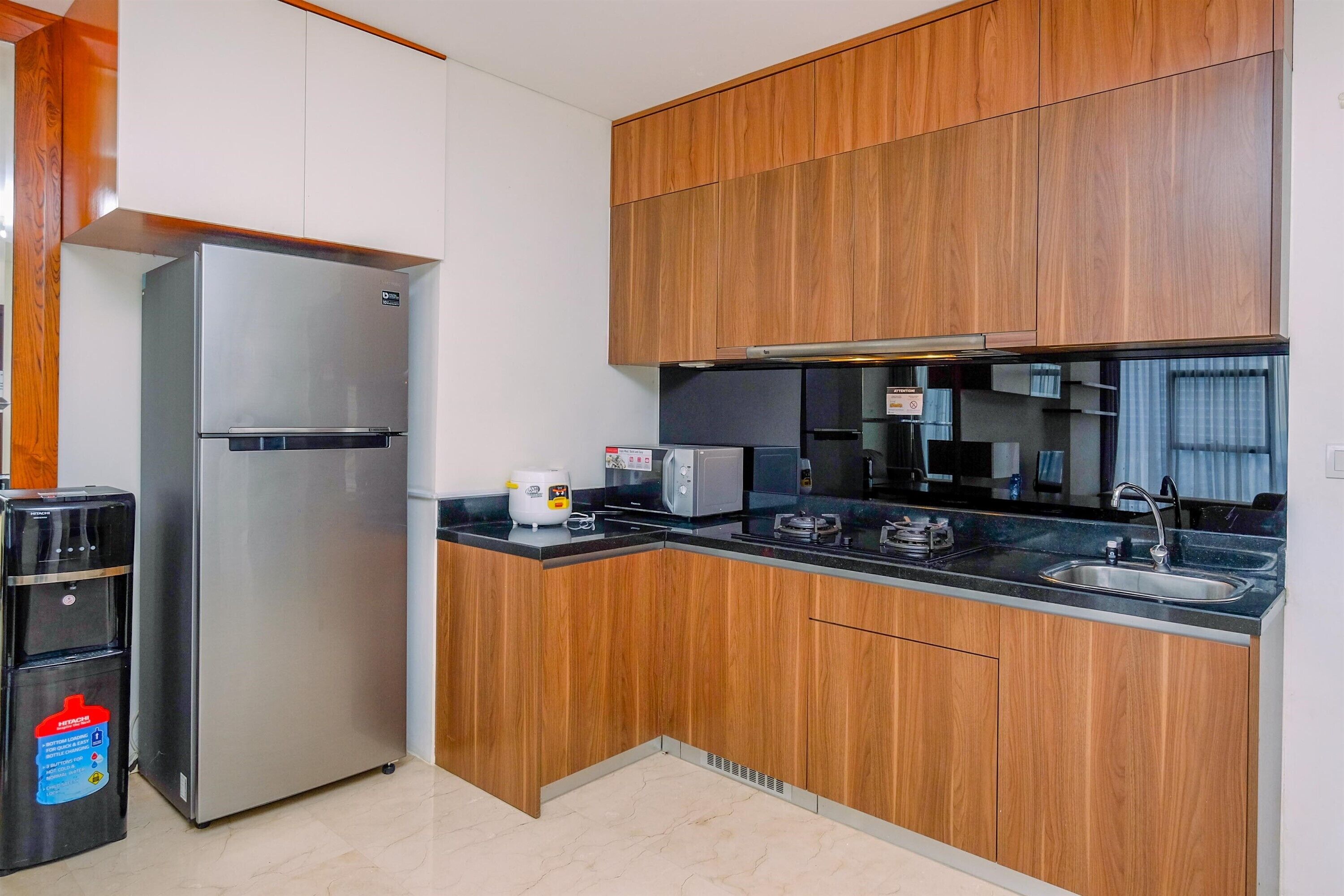 A modern kitchen with wooden cabinets, a stainless steel refrigerator, a built-in oven, and a sink.
