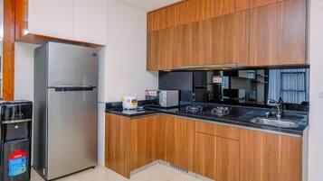 A modern kitchen with wooden cabinets, a stainless steel refrigerator, a built-in oven, and a sink.