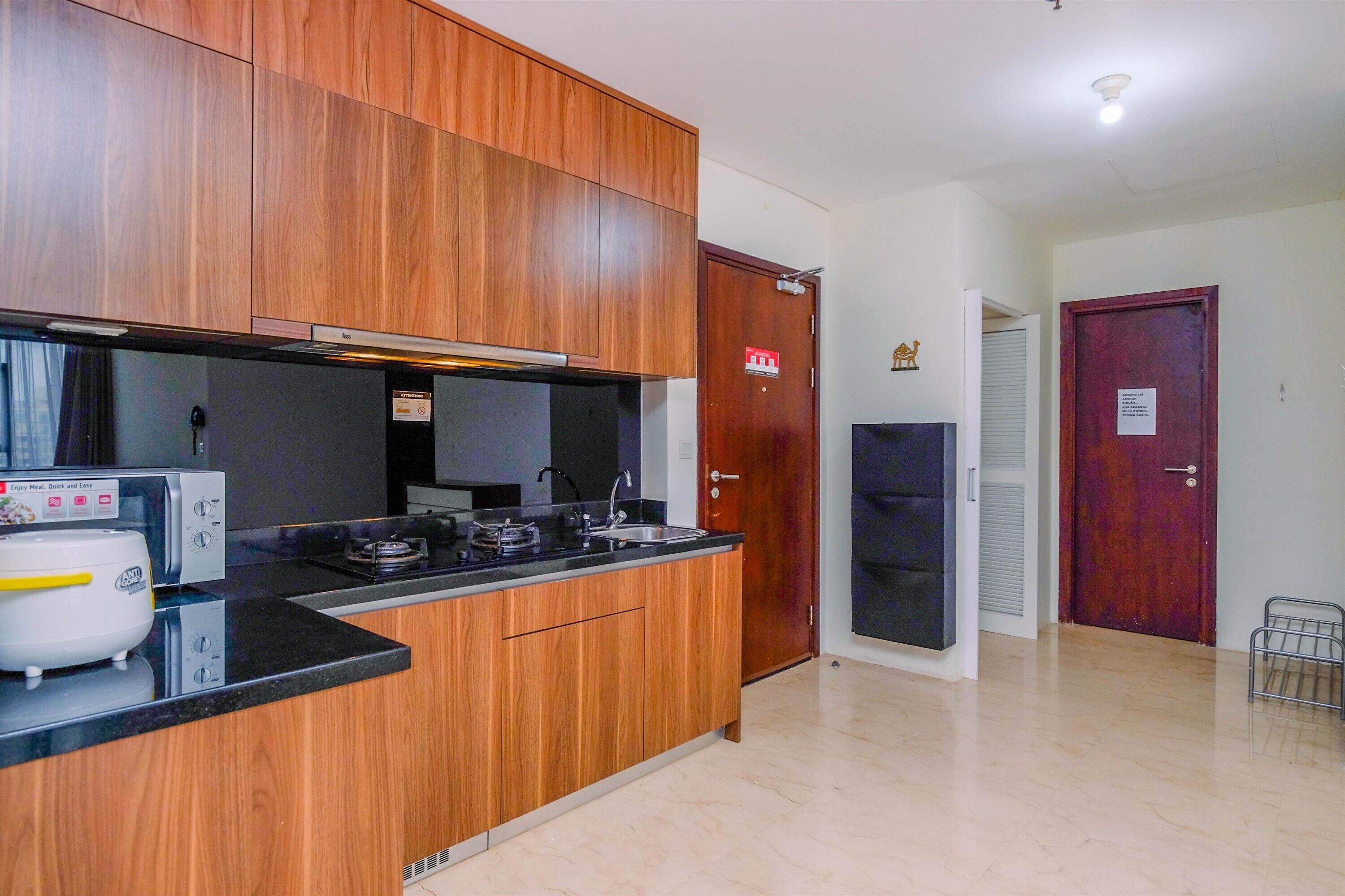 A compact kitchen with wooden cabinets, a black countertop, and a built-in microwave.