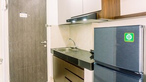 Una cocina compacta con un refrigerador de acero inoxidable, un fregadero y armarios de madera.