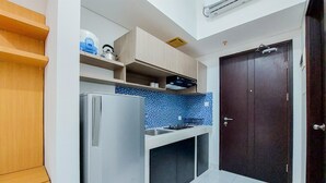 Una cucina compatta con frigorifero, lavandino e una porta in legno scuro.