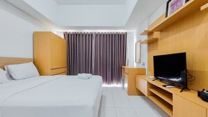 Una camera d'albergo con un letto, una televisione, una scrivania in legno e una finestra con tende.