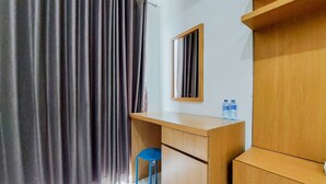 Una stanza con una scrivania in legno, una sedia blu, uno specchio e una finestra con tende.