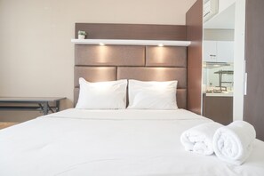 A neatly made bed with white linens and pillows, a bedside table, and a wall-mounted shelf with a small plant.