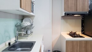 A compact kitchen with a sink, dish rack, and a gas stove.