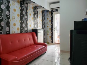 A room with a red sofa, a TV, and a patterned wall.