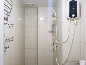 A modern bathroom with white tiles, a shower with a control panel, and towel racks.
