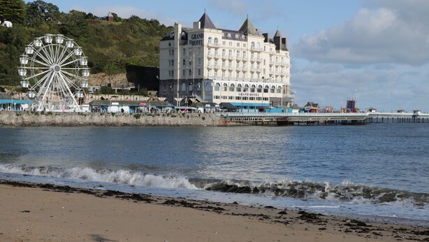 Un hotel sul lungomare con una grande ruota panoramica e un molo che si protende nell'acqua.