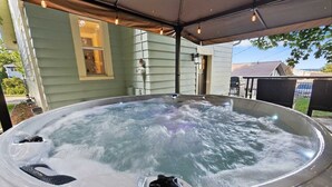 An outdoor hot tub with a metal roof and a house in the background.