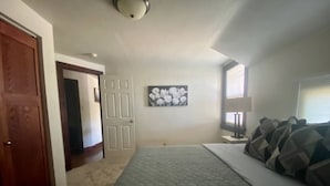 A bedroom with a bed, a door, a wall-mounted picture, and a window. - The Tiny Piney  - Live. Work. Play. Downtown Green Bay! (Green Bay)