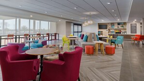 A modern lounge area with vibrant seating, a central table, and a kitchen area in the background. - Home2 Suites by Hilton Scottsdale North (Scottsdale)