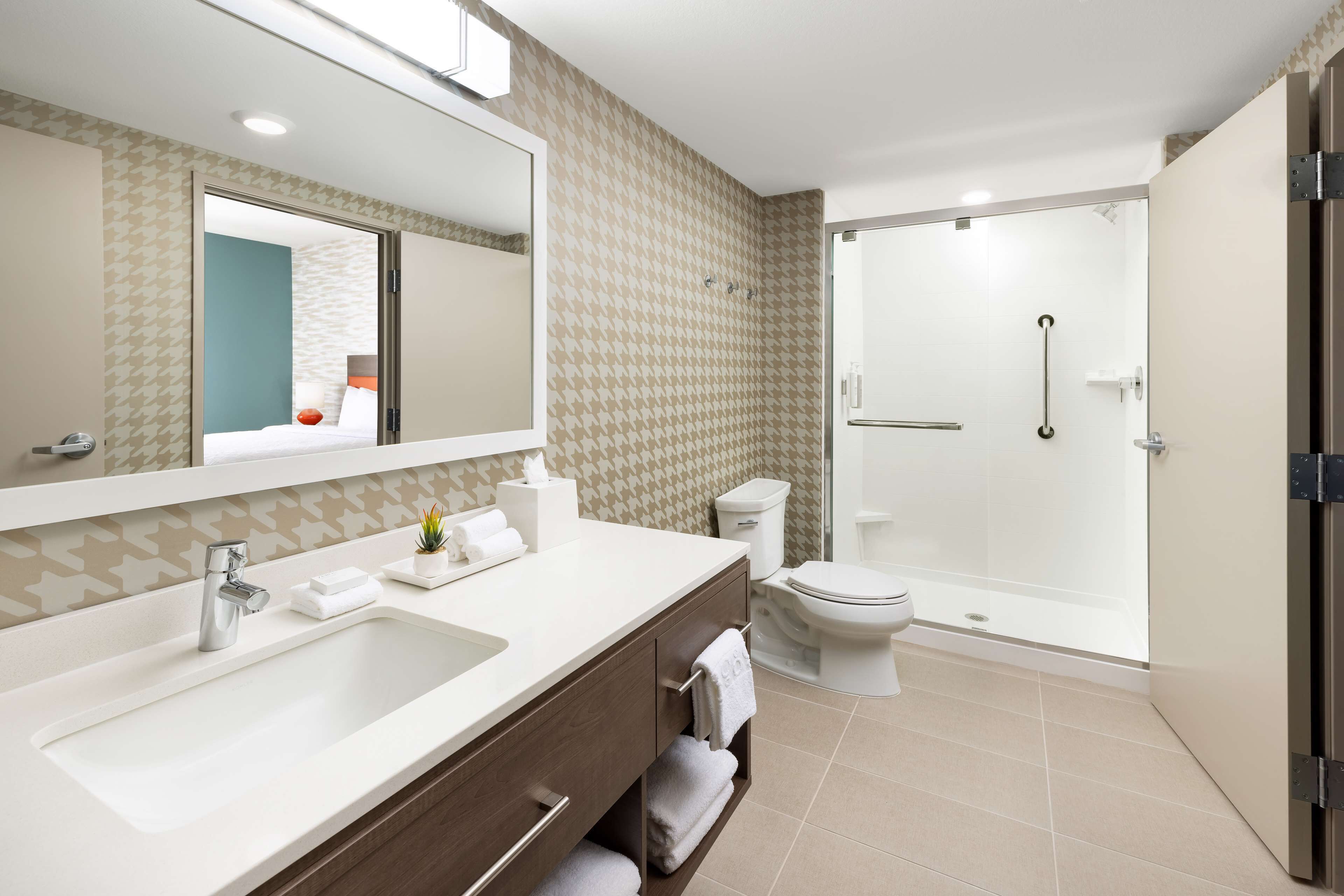 Een moderne badkamer met een ruime wastafel, spiegel, toilet en inloopdouche.