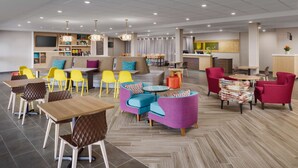 A modern hotel lobby with a variety of seating options, including tables and chairs, a sofa area, and a reception desk. - Home2 Suites by Hilton Scottsdale North (Scottsdale)